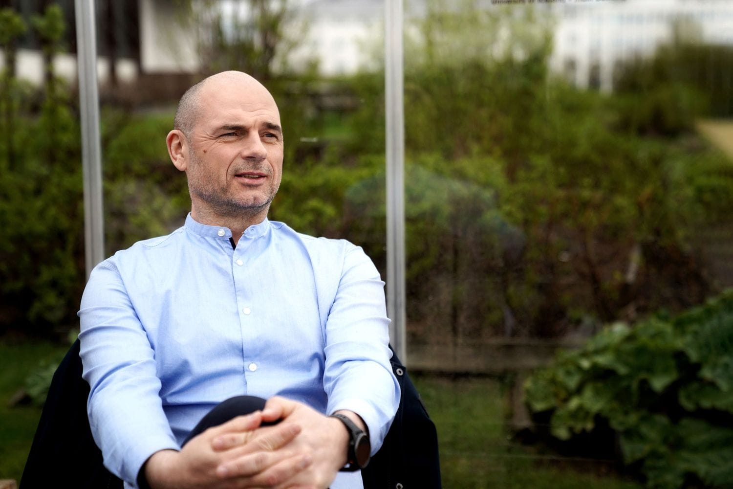 Sitjandi maður í stól í gróðurhúsi 