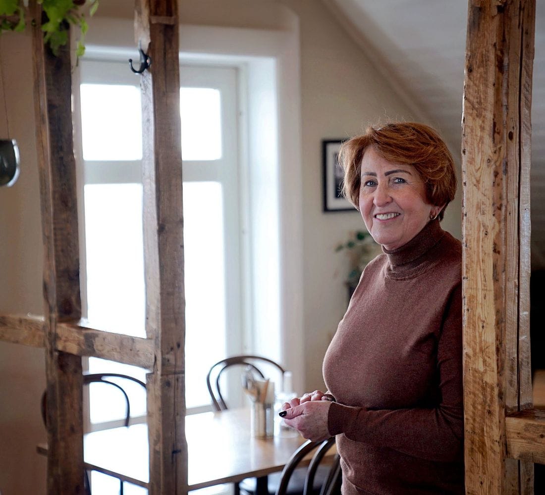 Kona horfir í myndavélina og stendur inn á veitingastað