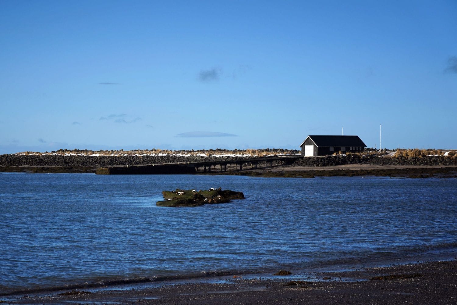 Hús, haf, bryggja og fjara