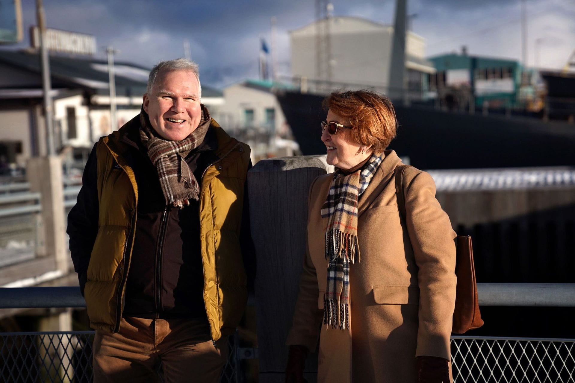 Kona og maður á bryggju að tala saman