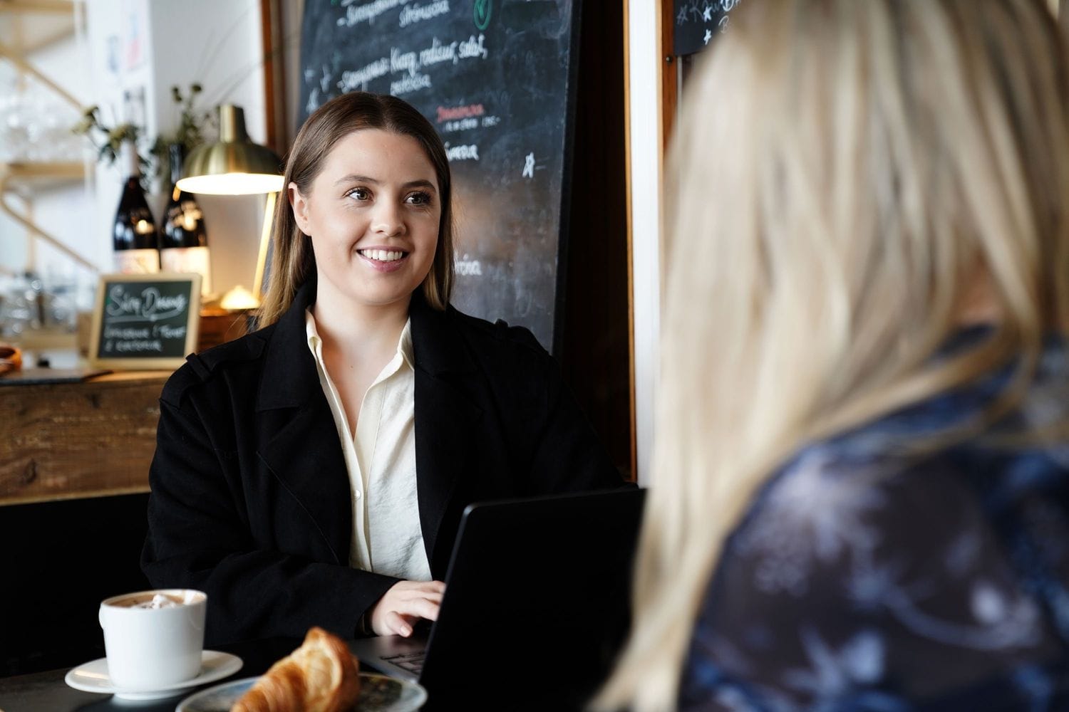 Ung kona á kaffihúsi með tölvu