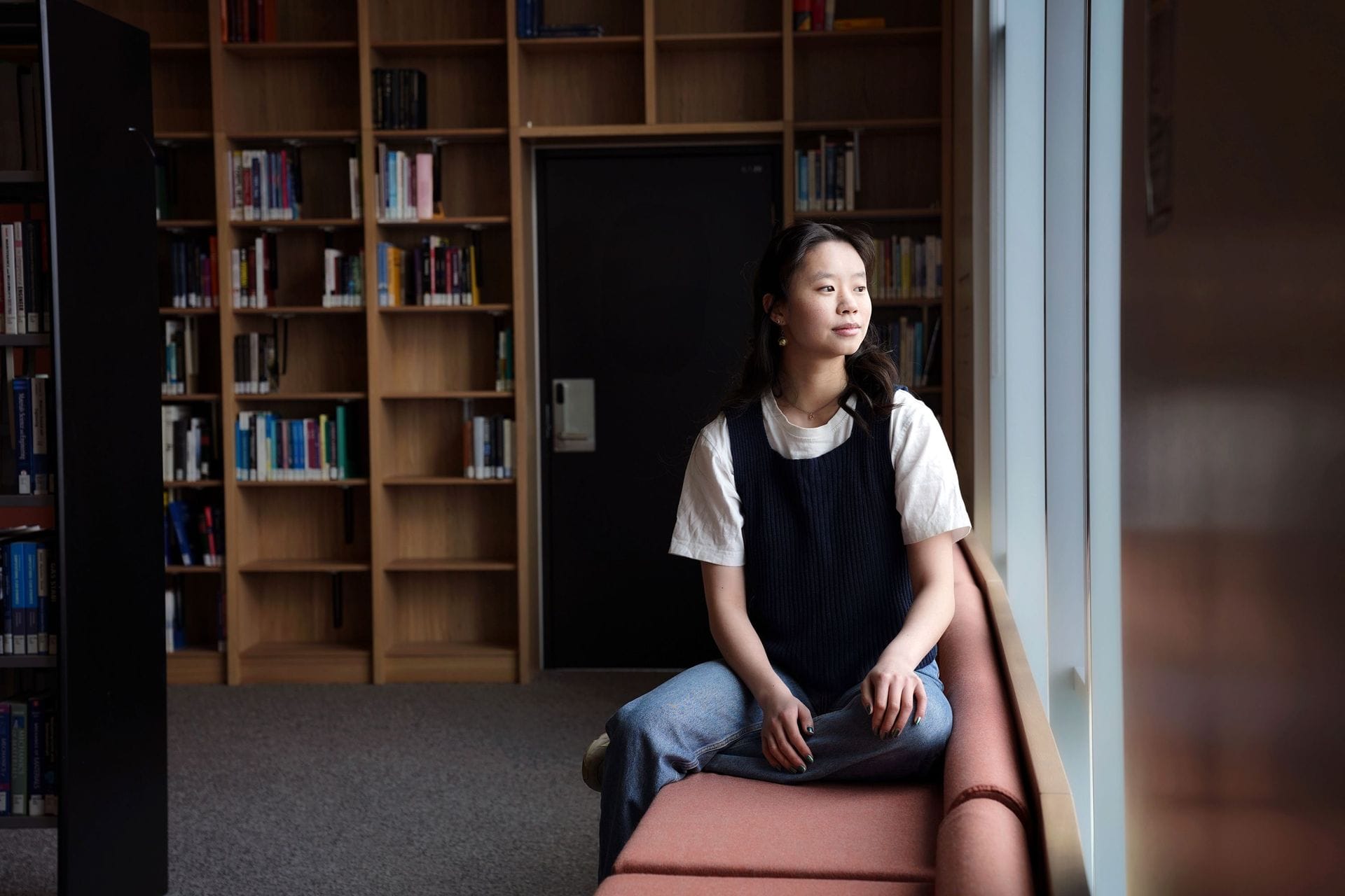 Ung kona horfir ekki í myndavél inn á bókasafni