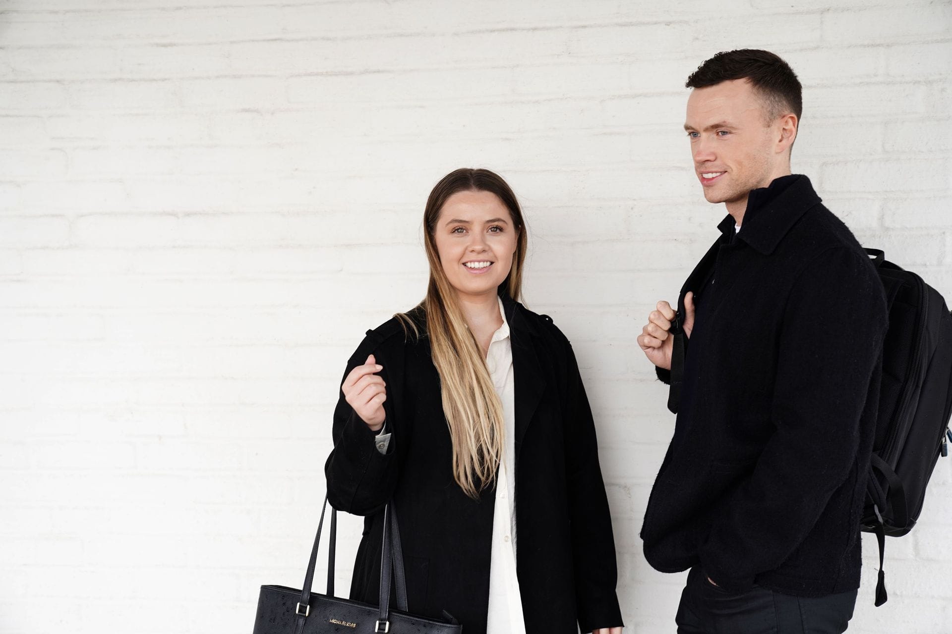 Ung kona og ungur maður standa við hvítan vegg