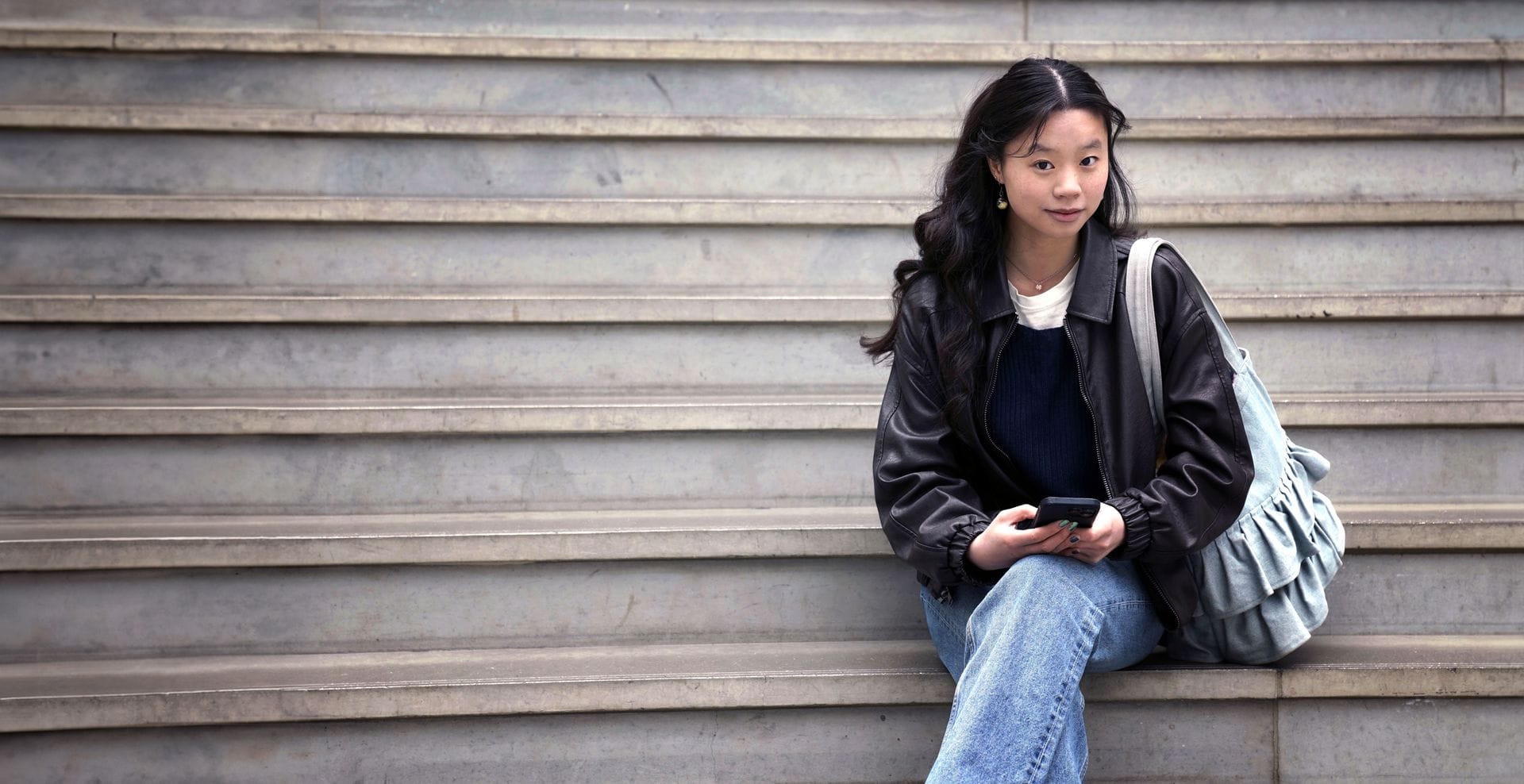 ung kona situr í tröppum og horfir í myndavél