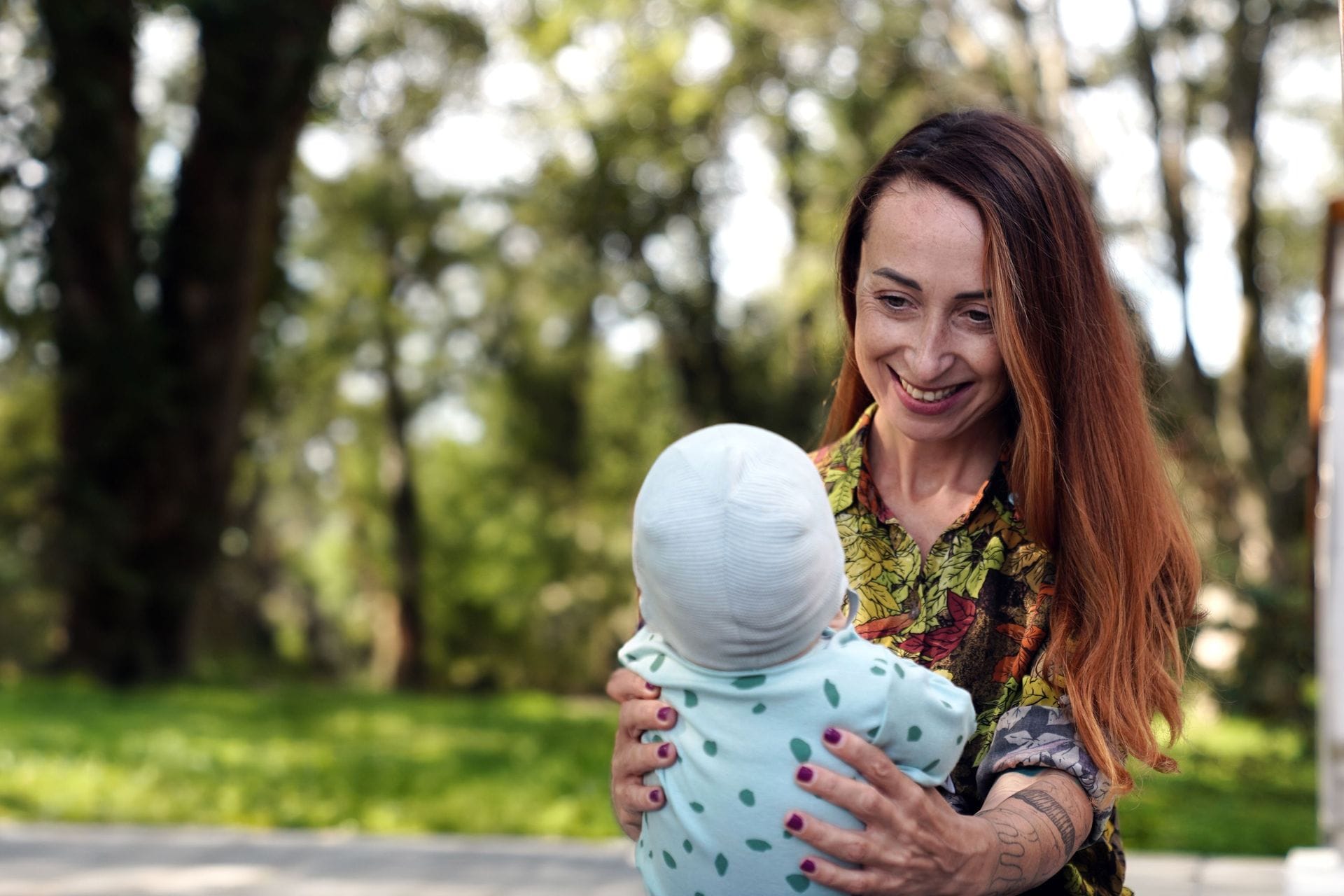 Ung kona situr með barn úti að sumri til