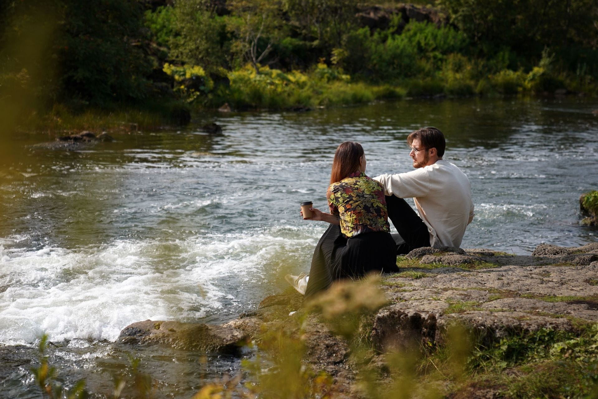 Ungur maður og ung kona tala saman á árbakka