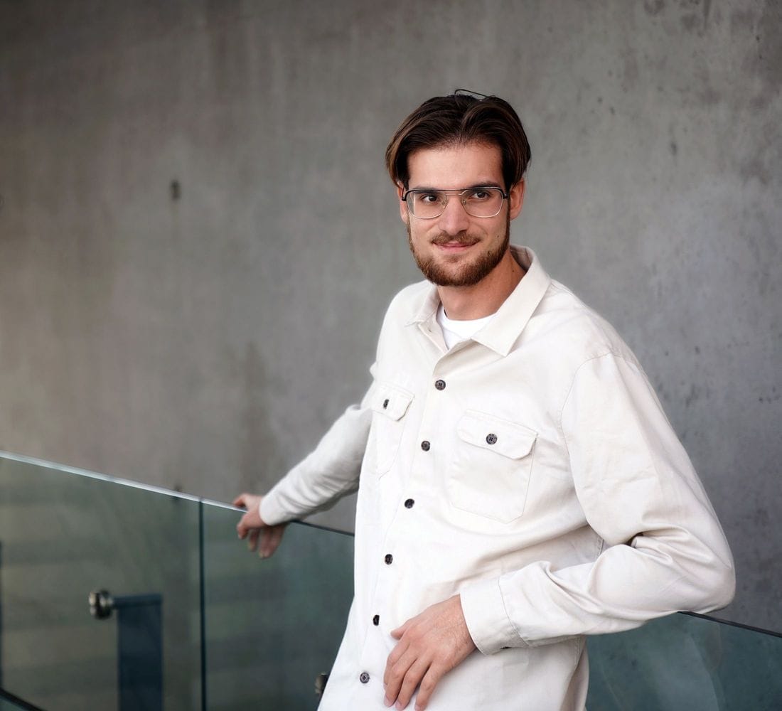 Ungur maður stendur við handrið og horfir ekki í myndavélina